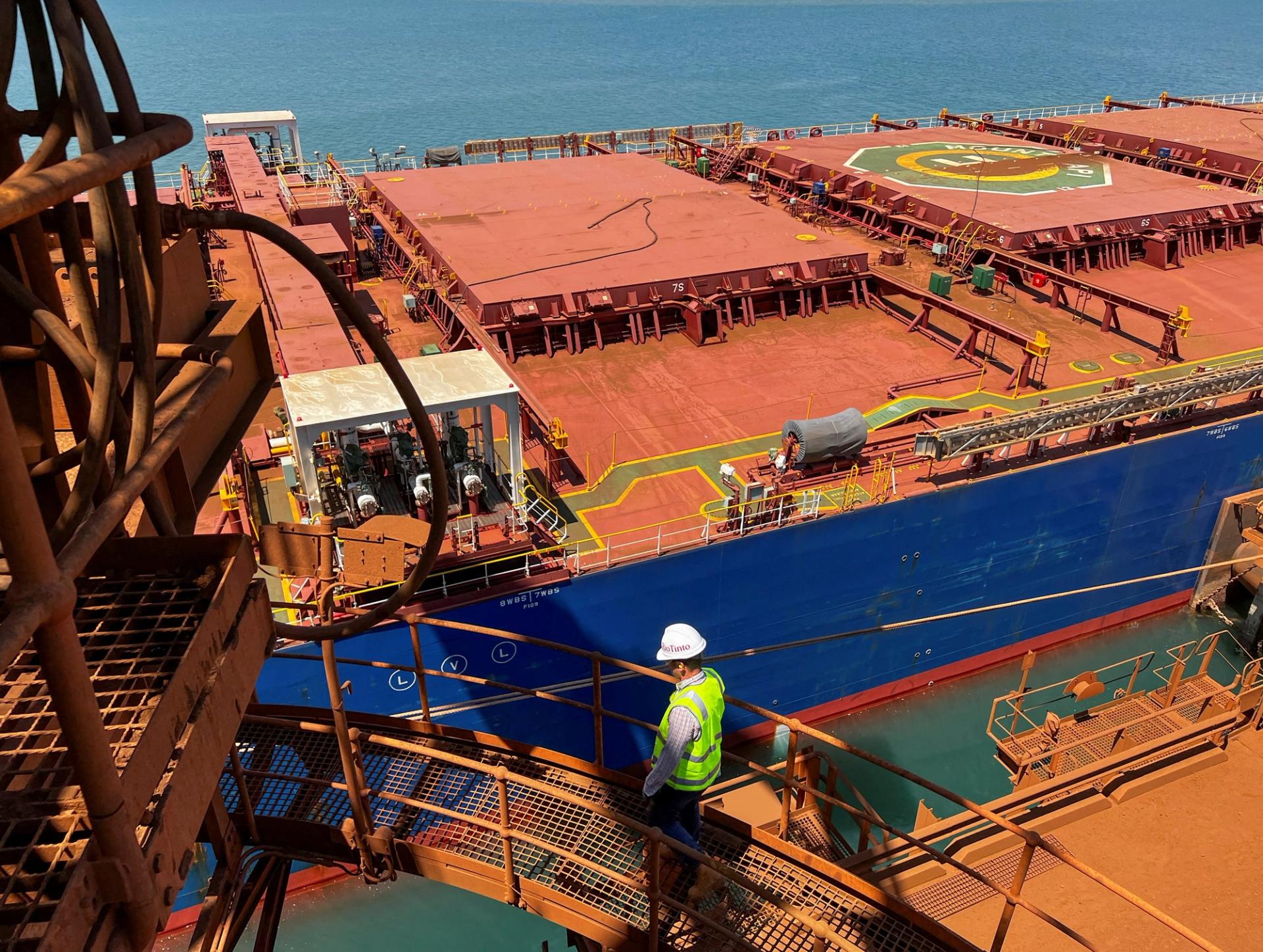 A visitor walks in front of an iron ore carrier at Rio Tinto’s Port Dampier operations in Western Australia.