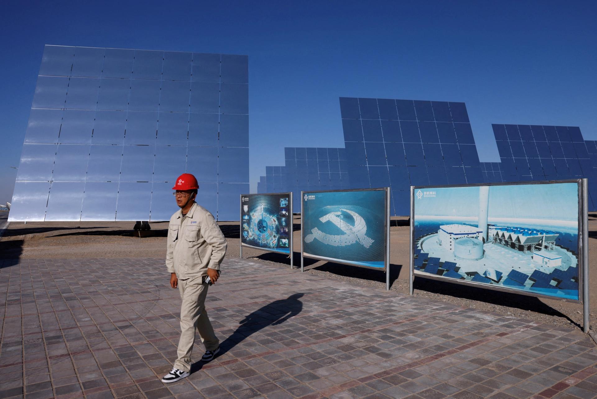 An employee walks near fields of heliostat mirrors at the site of Dunhuang Shouhang 100MW Tower Solar Thermal Power Generation Project, China, 2024.