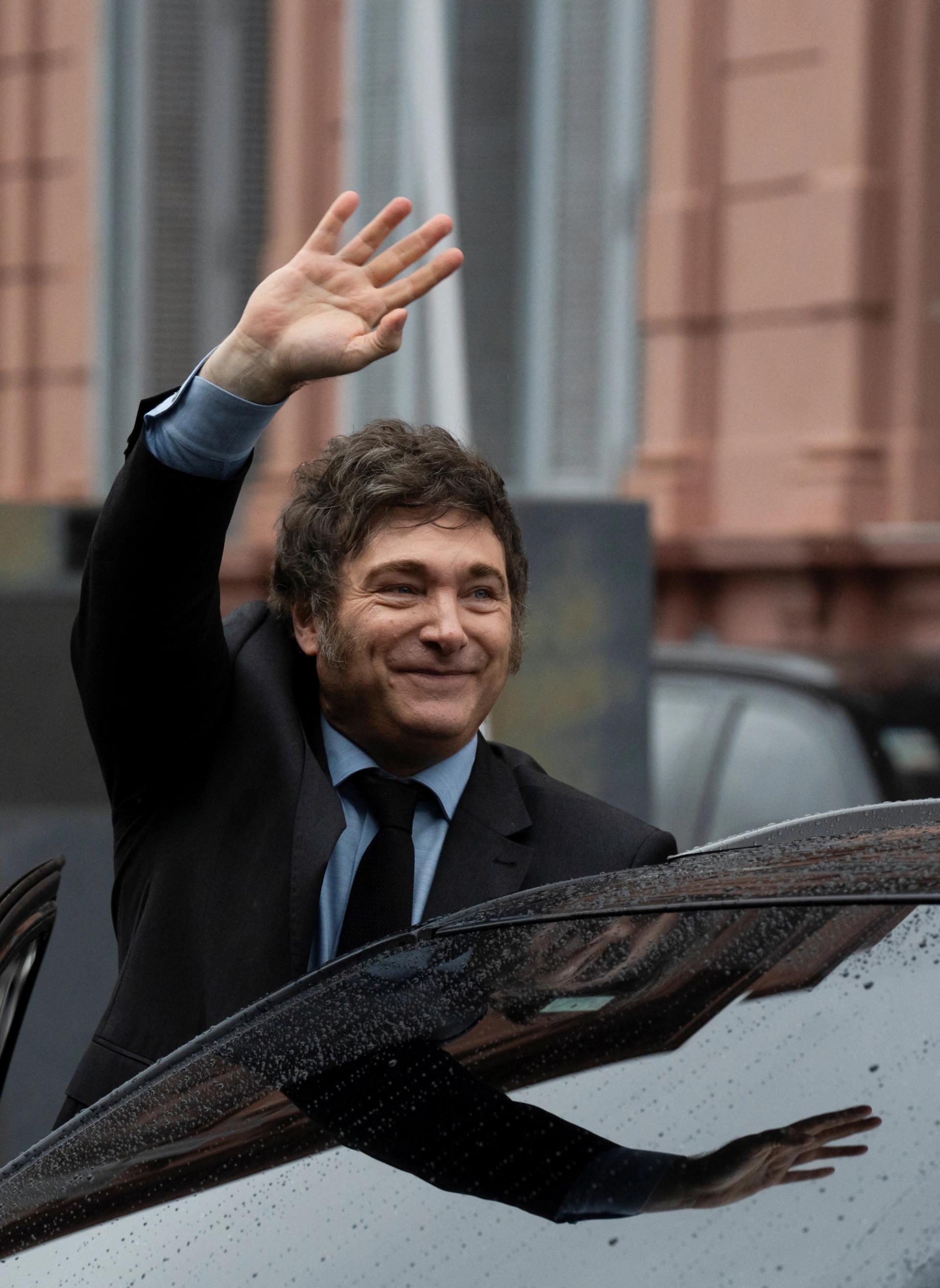 Javier Milei waves from his car after a meeting with President Emmanuel Macron in Buenos Aires