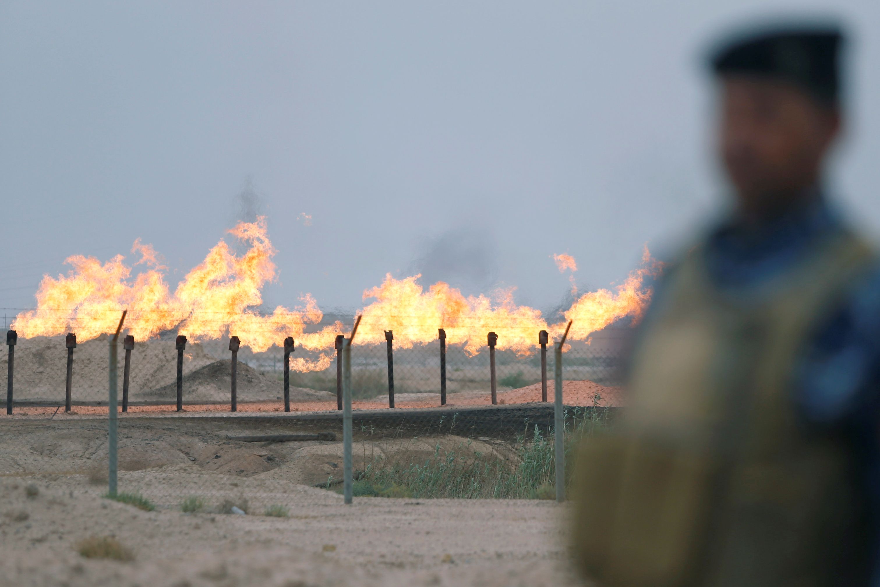 A member of the Iraqi security forces stands guard at an oil burner in al-Zubair oil field, near Basra, Iraq
