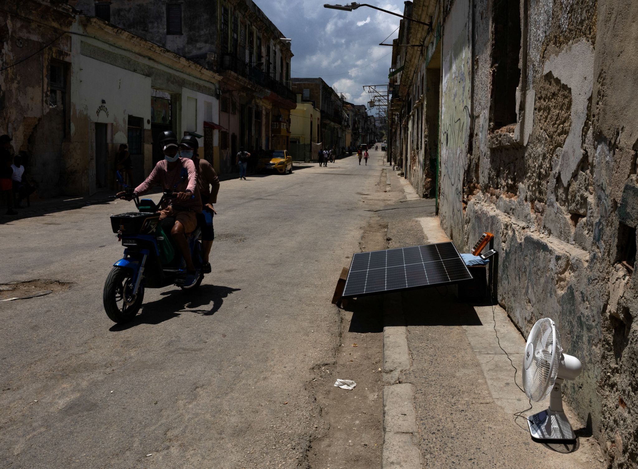A person rides in a motorcycle past a solar panel in Havana, Cuba.