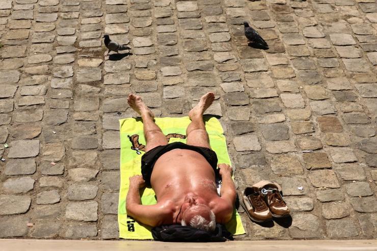 A Parisian man sunbathes shirtless in the street