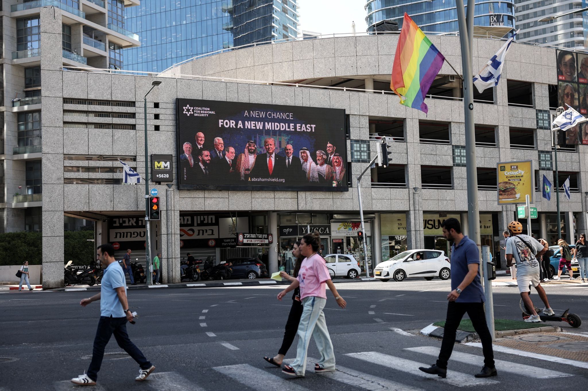 People walk by a billboard sponsored by the Coalition for Regional Security calling for the expansion of the Abraham Accords, in Ramat Gan