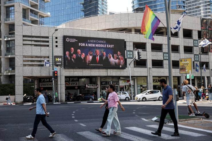 People walk by a billboard sponsored by the Coalition for Regional Security calling for the expansion of the Abraham Accords, in Ramat Gan