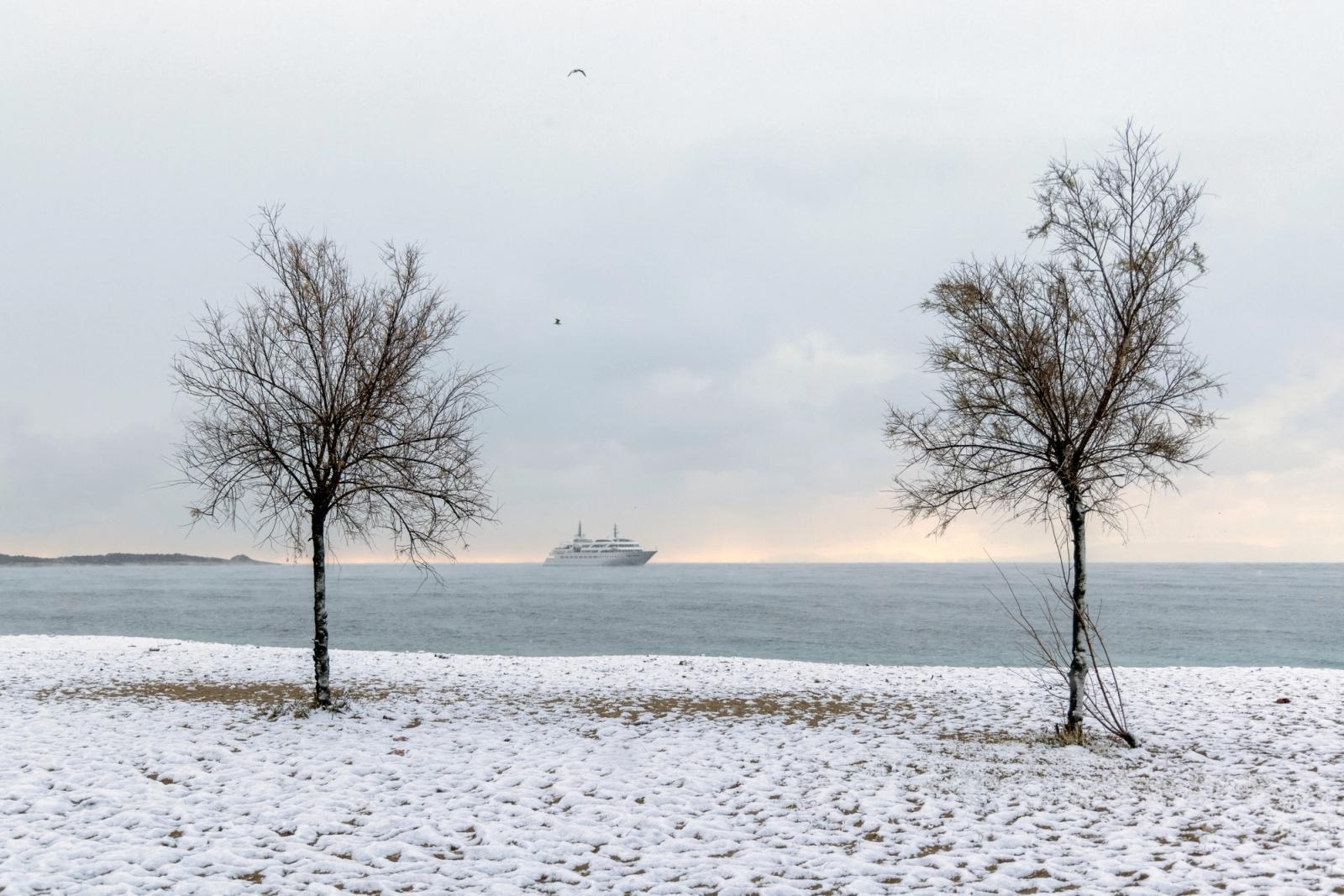 Snows covers a beach in Glyfada suburb, as a cruise ship sails in the background, during snowfall in Athens, Greece, February 6, 2023.