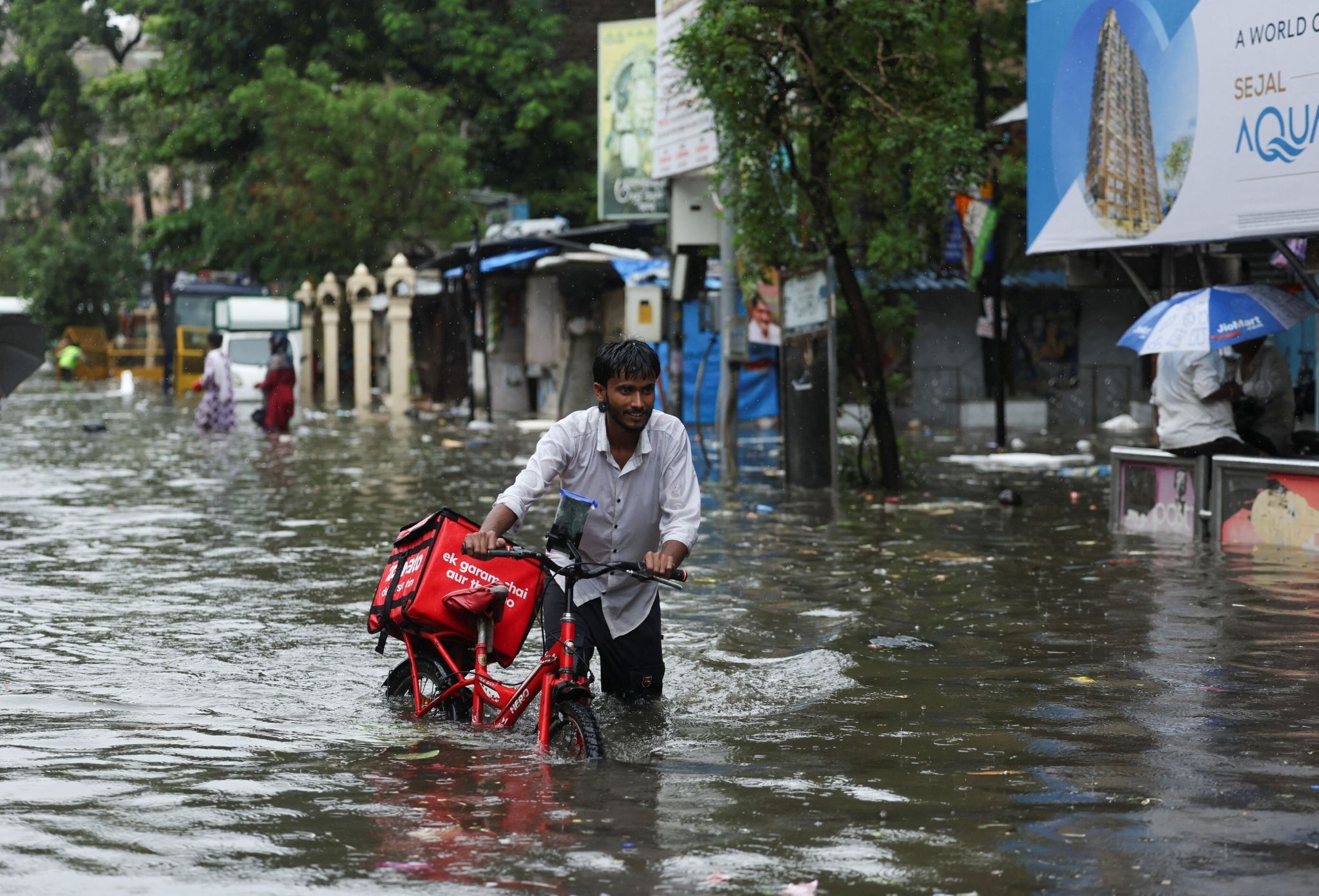 An Indian food delivery courier wades through flood waters