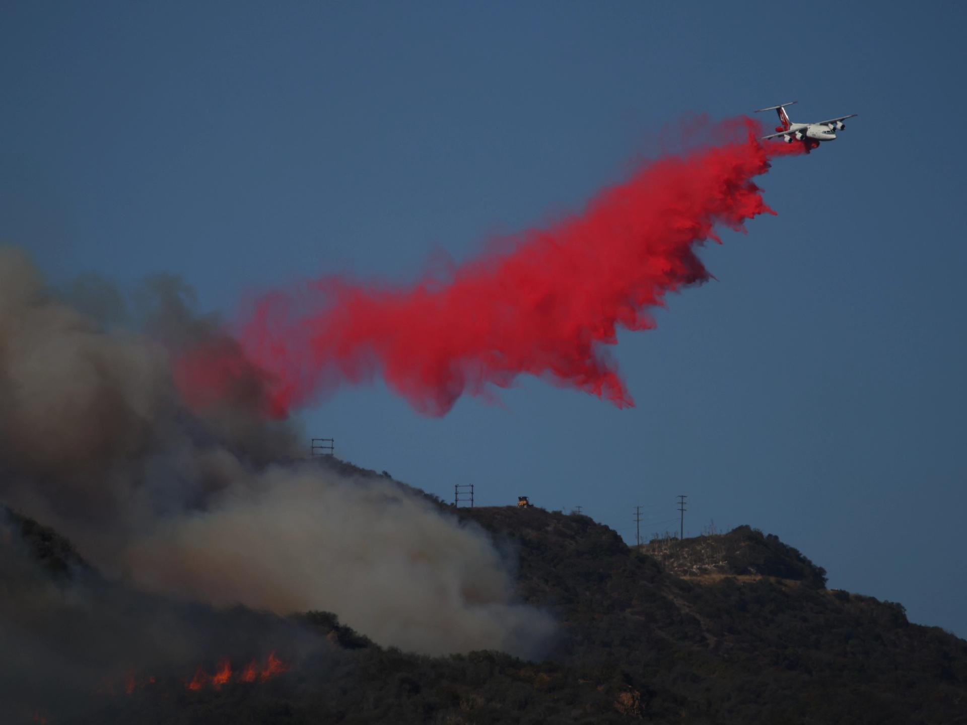 A plane drops fire retardant over Pacific Palisades as wildfires rage.