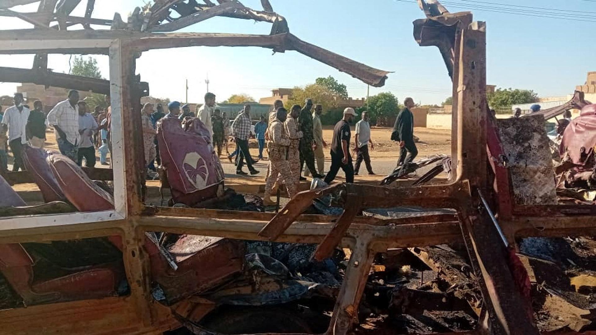 People walk past a destroyed vehicle, following shelling by the Rapid Support Forces, in Omdurman, Sudan, December 10, 2024.