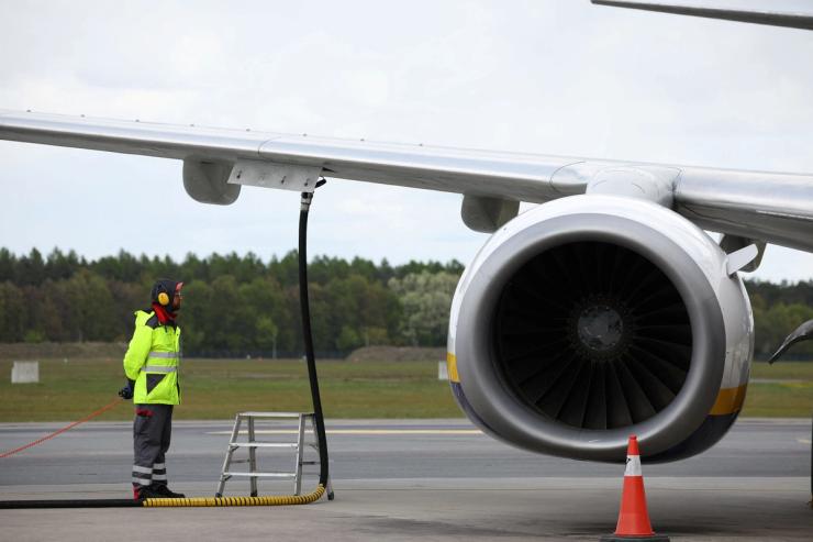 A ground crew member refuels an aircraft with jet fuel.