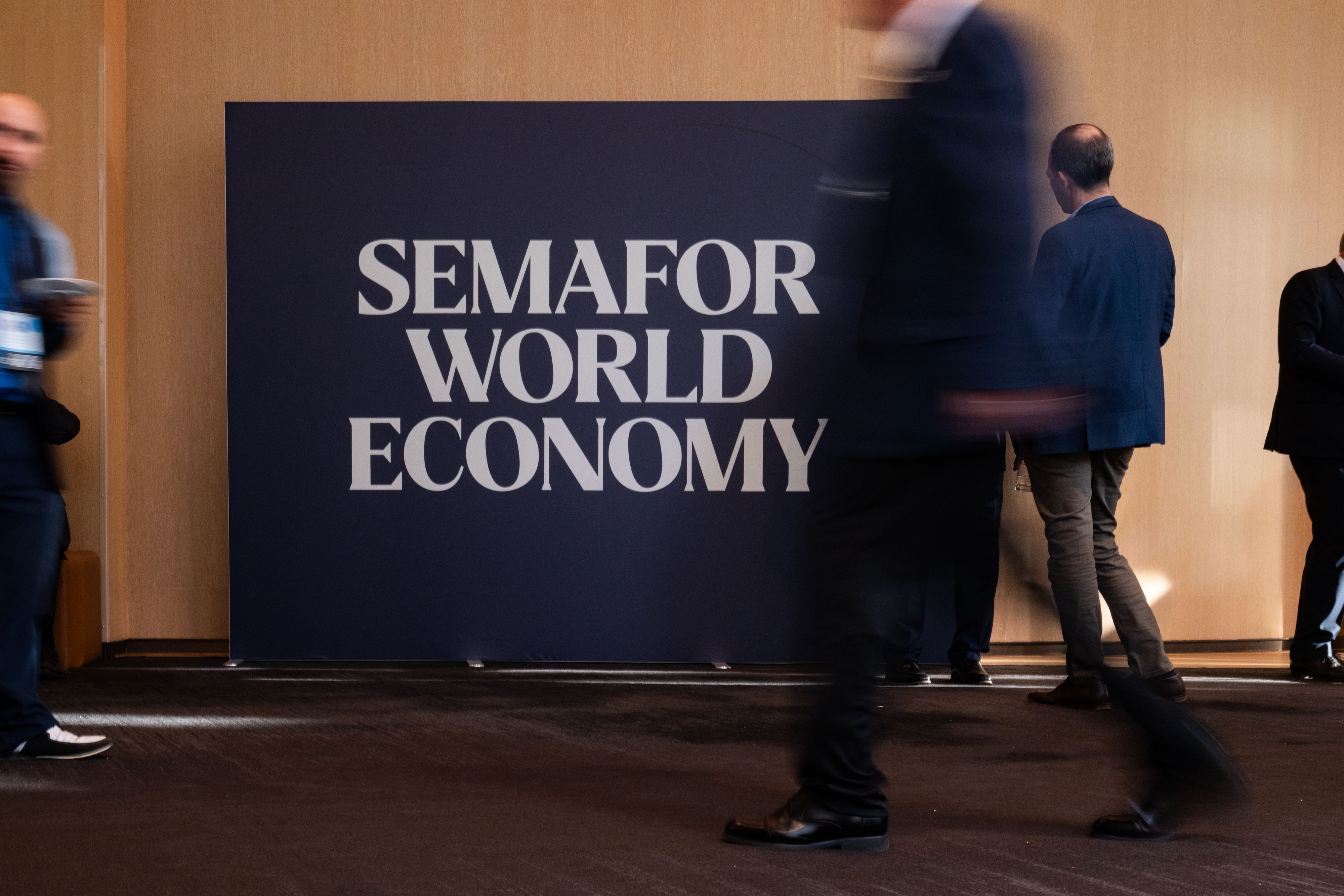 Semafor World Economy signboard with people walking