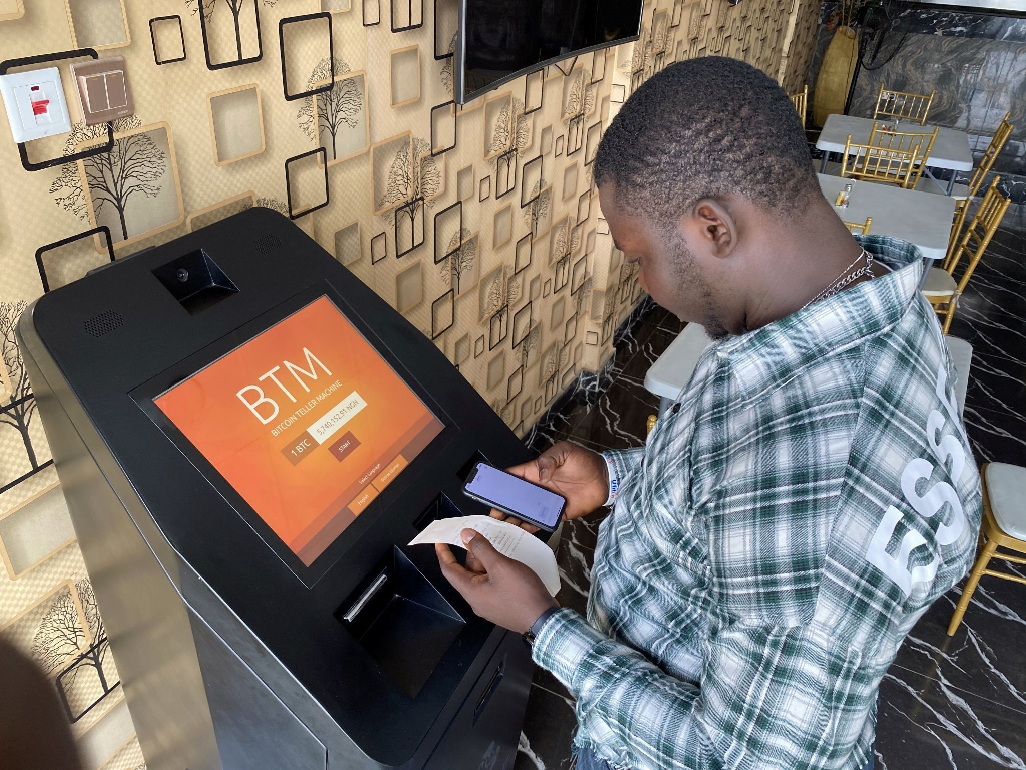 A bitcoin user checks the receipts after buying bitcoins with naira on Bitcoin Teller Machine in Lagos.