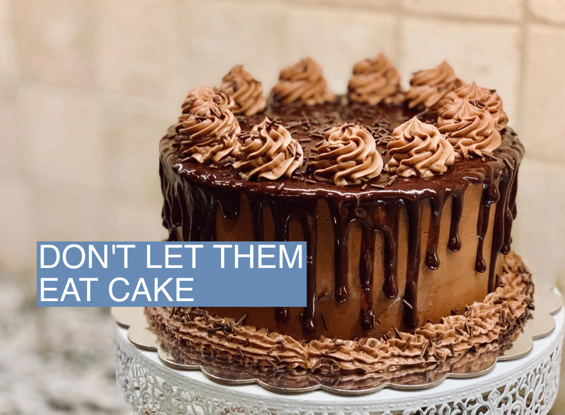 A chocolate cake sits on a pedestal.