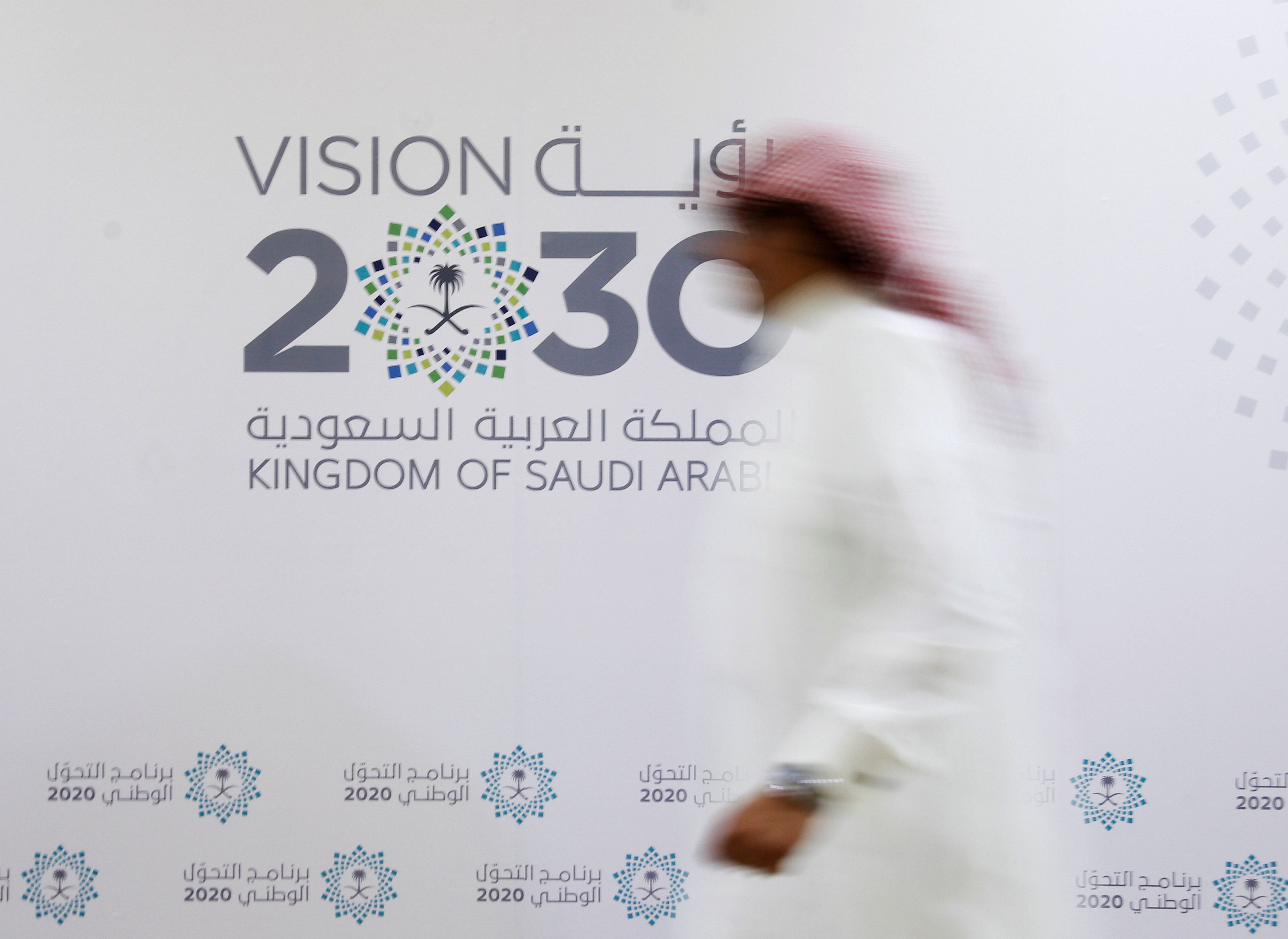 A Saudi man walks past the logo of Vision 2030 after a news conference in Jeddah.