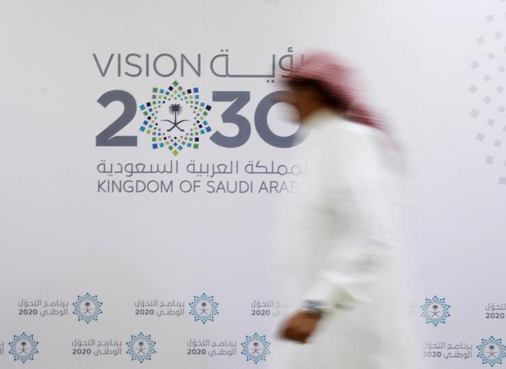 A Saudi man walks past the logo of Vision 2030 after a news conference in Jeddah.