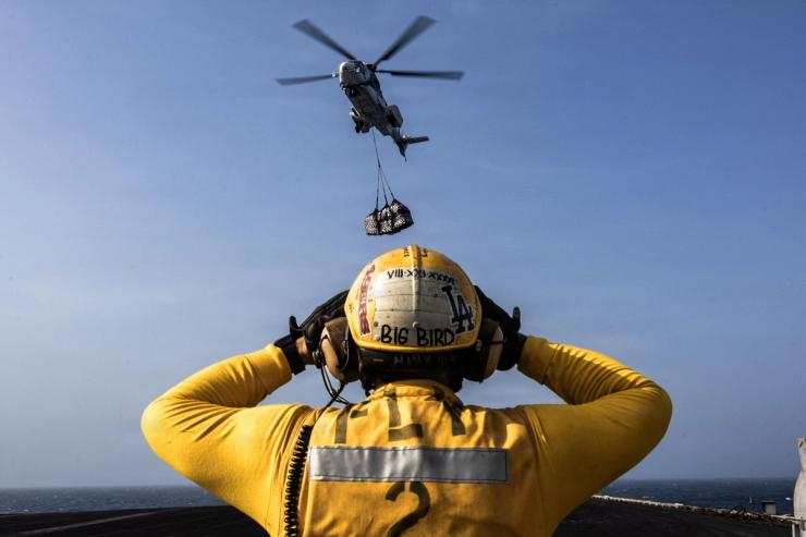 A US Navy sailor directs a Eurocopter AS-332 Super Puma helicopter on a US aircraft carrier
