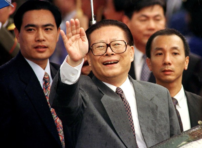 Chinese President Jiang Zemin smiles through the rain and waves to a crowd upon his arrival in Hong Kong June 30, 1997.