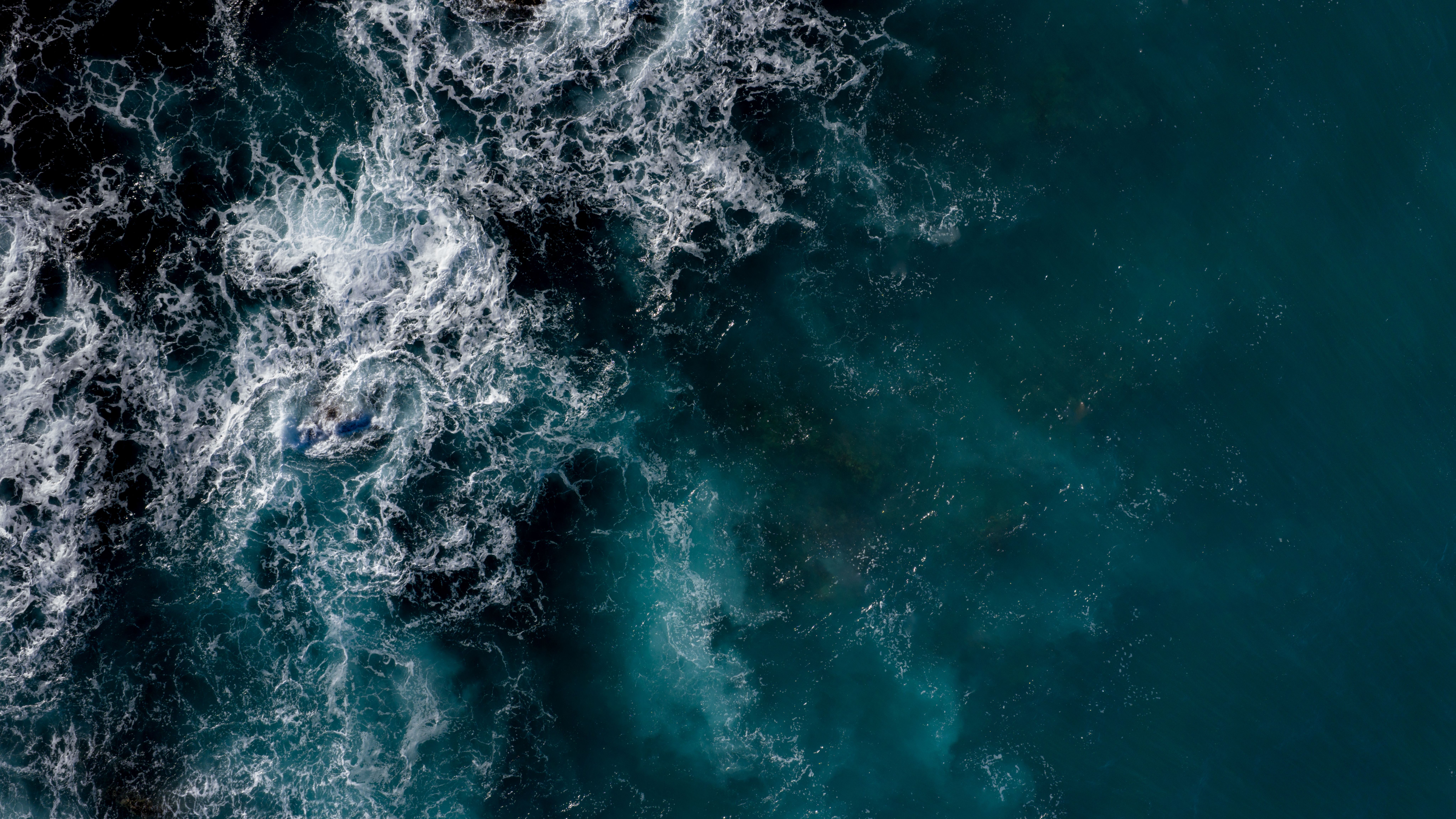 A breathtaking aerial view captures the turquoise ocean as white water swirls with the tide. 