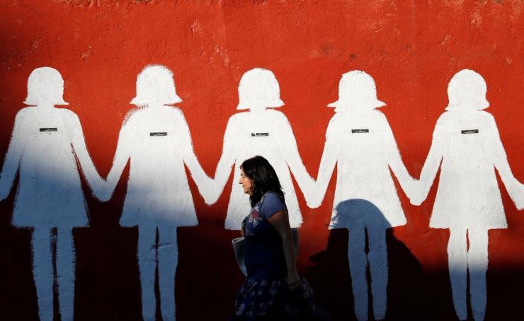 A woman walking past an anti-femicide mural in Rome.