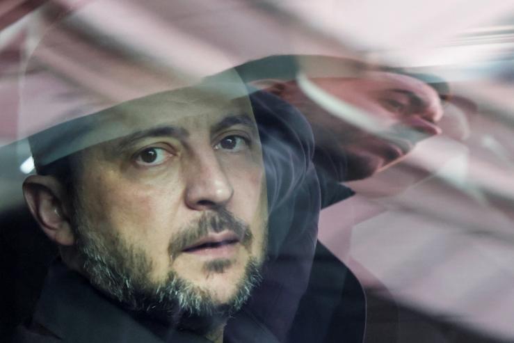 A security member is reflected on the window as Ukraine’s President Volodymyr Zelenskiy sits inside a vehicle