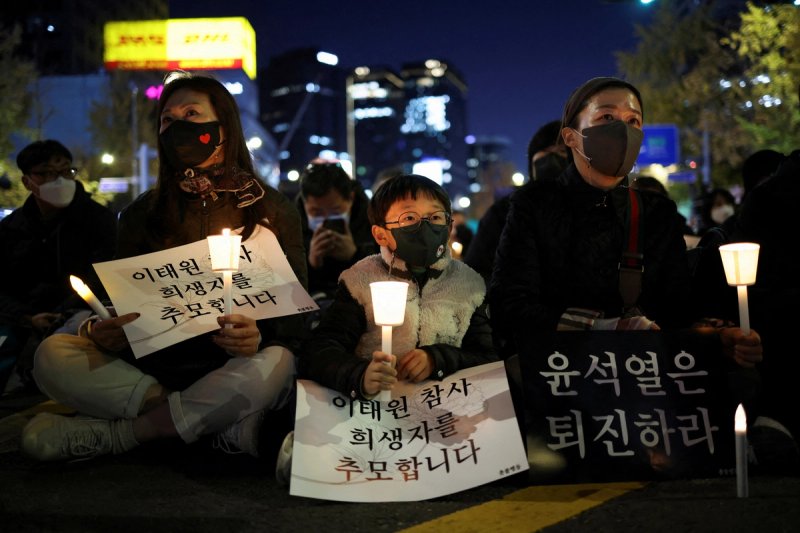 People hold placards as they attend a candlelit vigil to commemorate the victims of the crowd crush that happened during Halloween festivities, at Seoul City Hall Plaza, in Seoul, South Korea